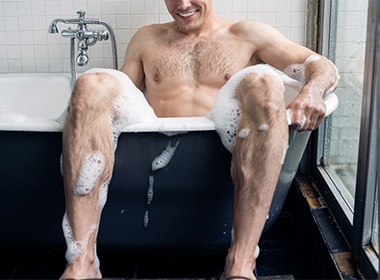 Man enjoying bath with dildo surrounded by foam